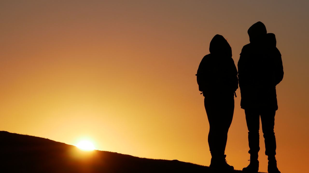 silhouette of people on top of hill during sunset