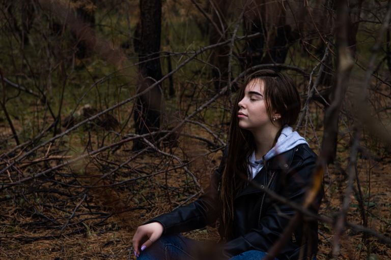 woman in black jacket sitting on brown grass during daytime