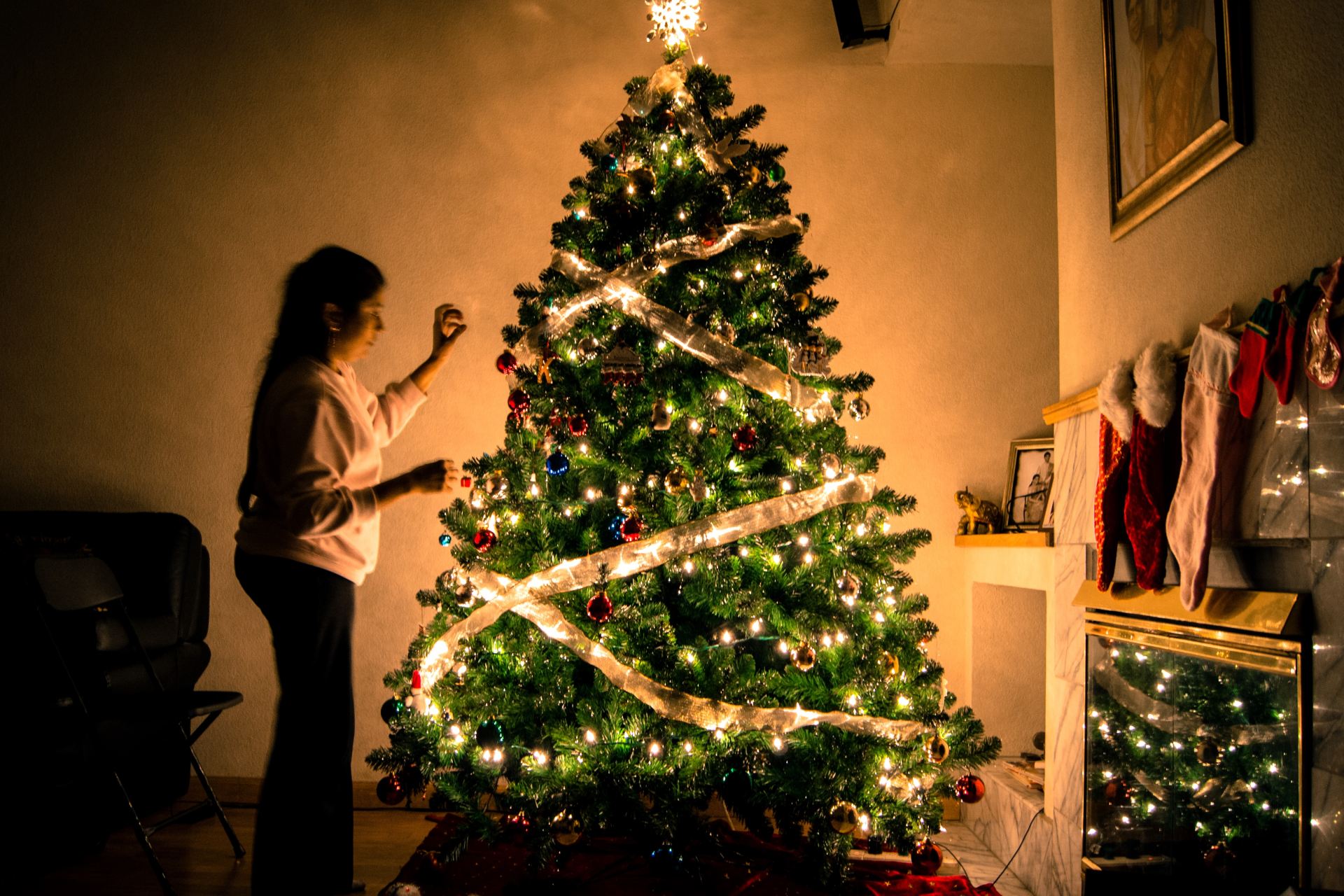 child standing in front of Christmas tree with string lights