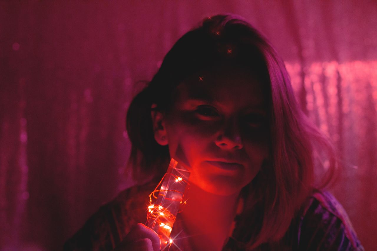 woman in black shirt holding string lights