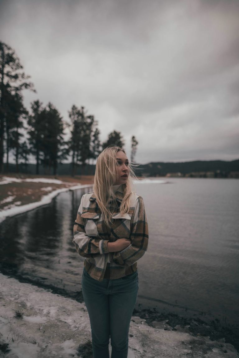 woman in gray jacket standing on gray concrete road during daytime