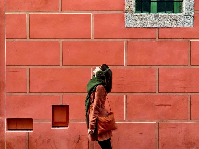 person in brown leather jacket standing in front of brown brick wall