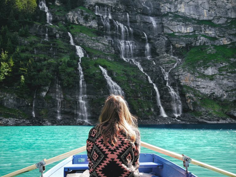 woman riding boat facing waterfalls