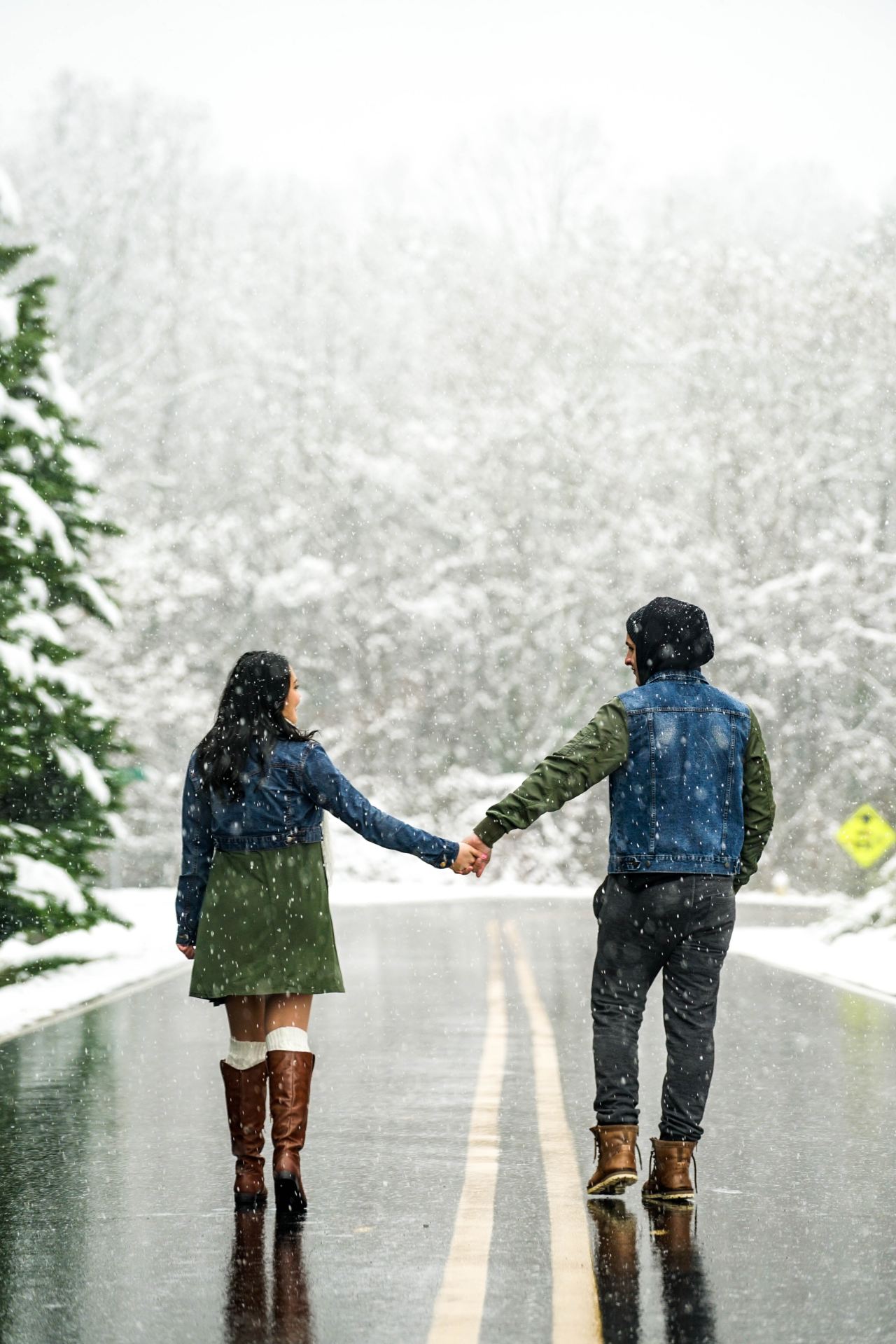 couple holding hands on wet road during daytime