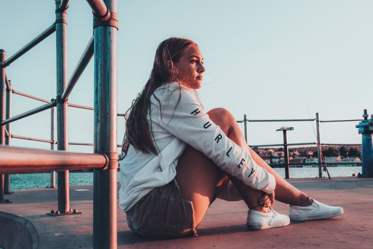 woman sits on ground near sea