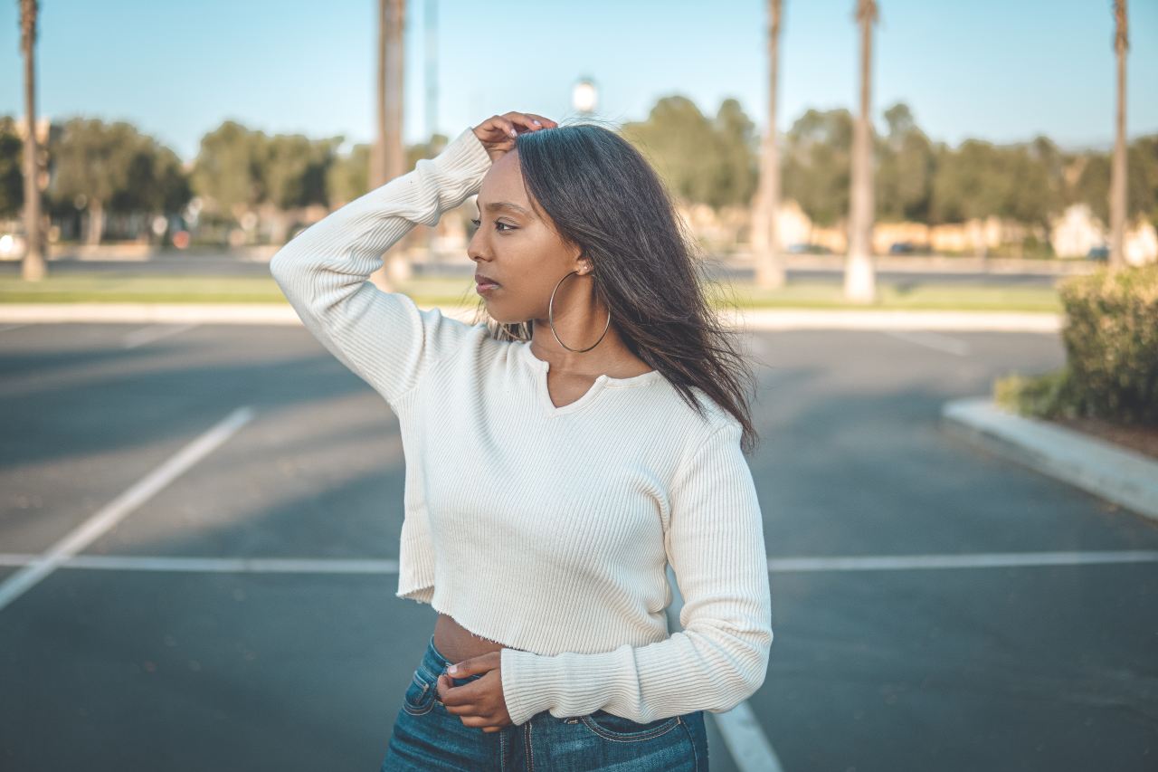 woman in white long sleeve shirt and blue denim jeans standing on road during daytime