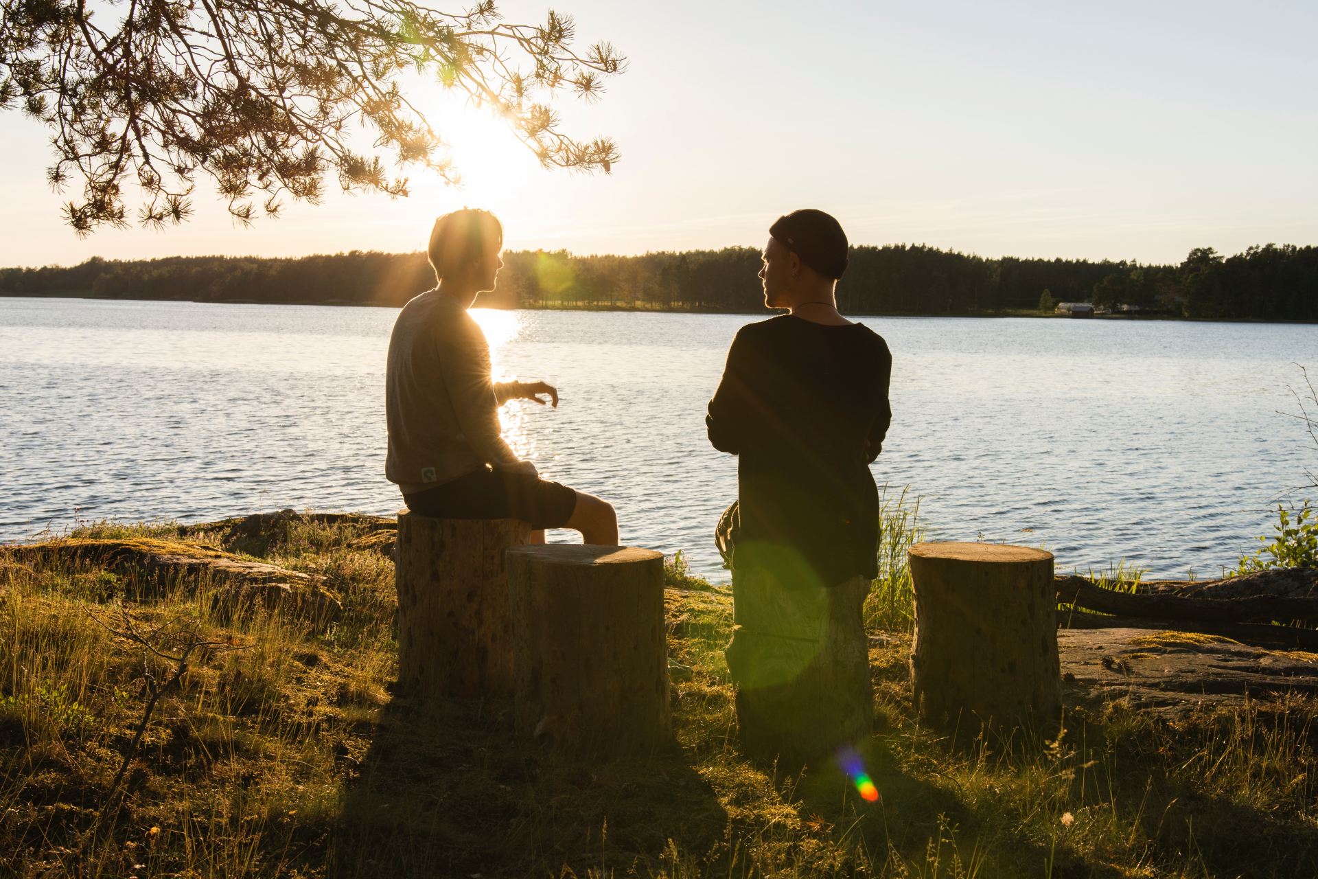 man in black jacket standing beside body of water during sunset