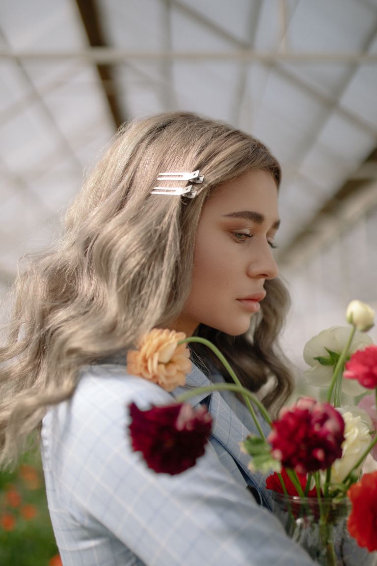 woman wearing grey shirt carrying flowers inside greenhouse