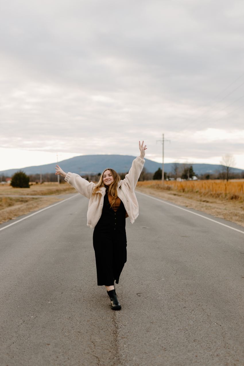 woman in black dress standing on road during daytime