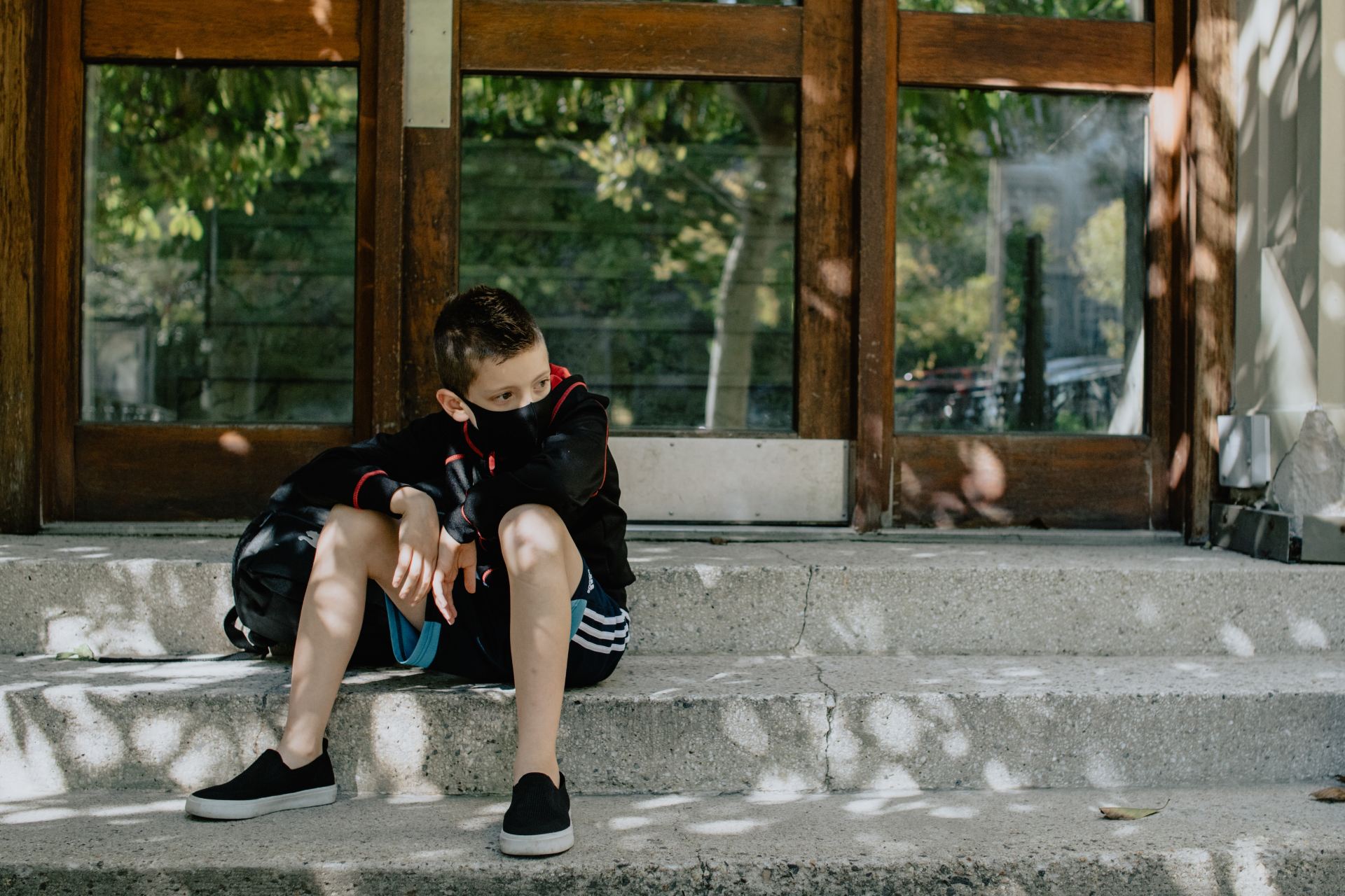 boy in black t-shirt and blue denim jeans sitting on concrete bench