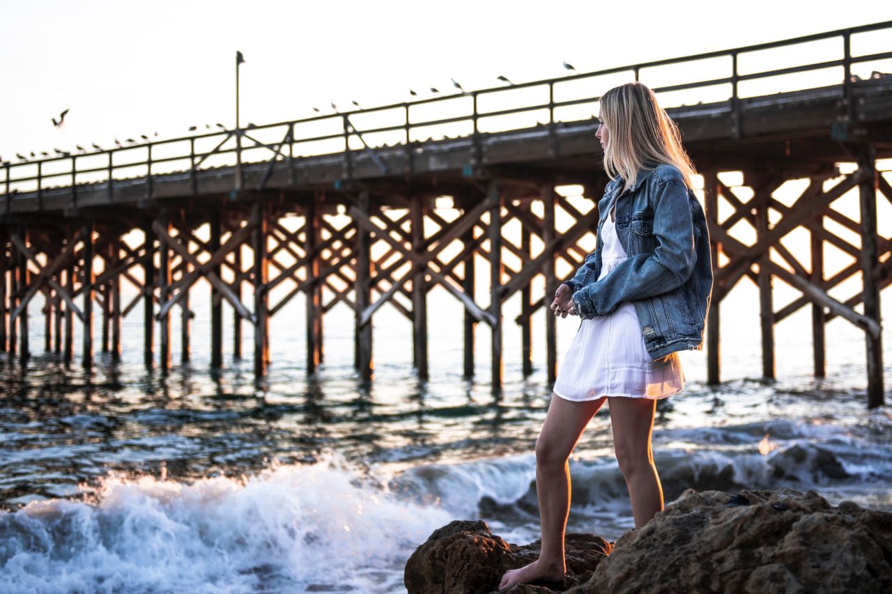 woman standing on seashore near bridge