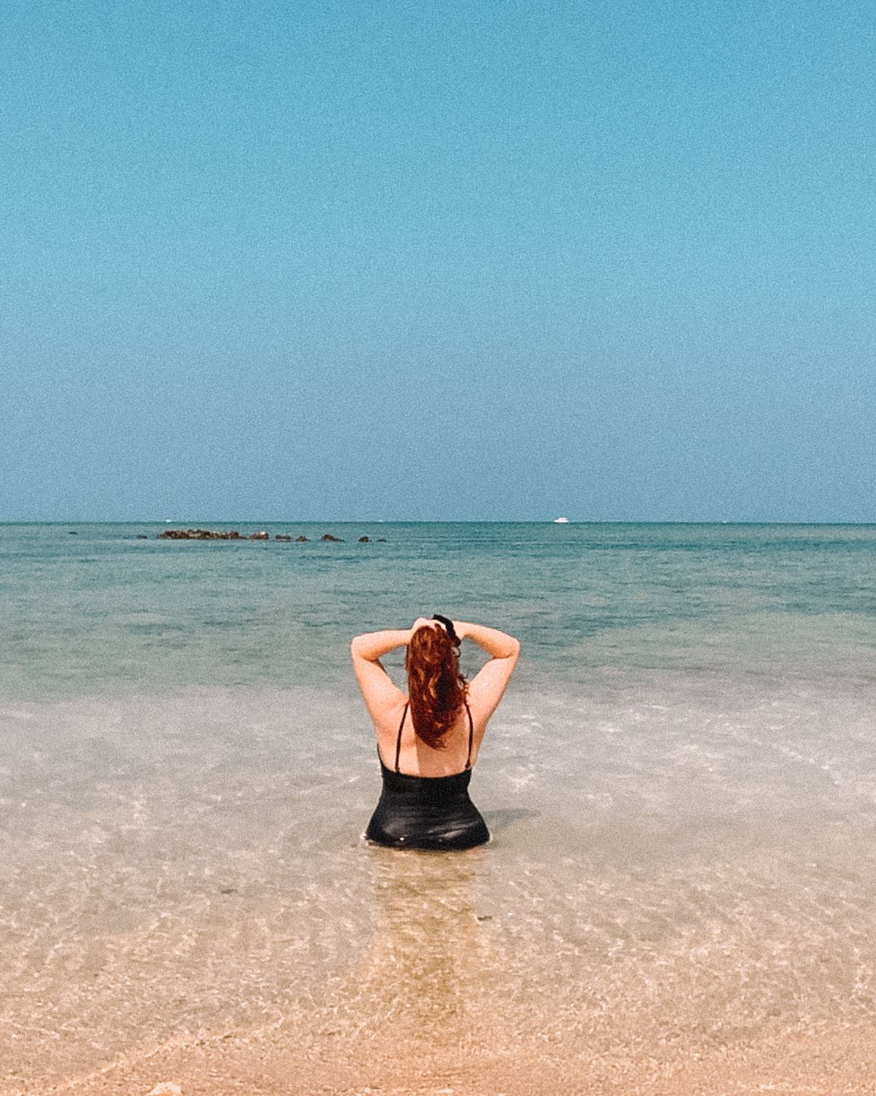 woman in black bikini lying on beach during daytime