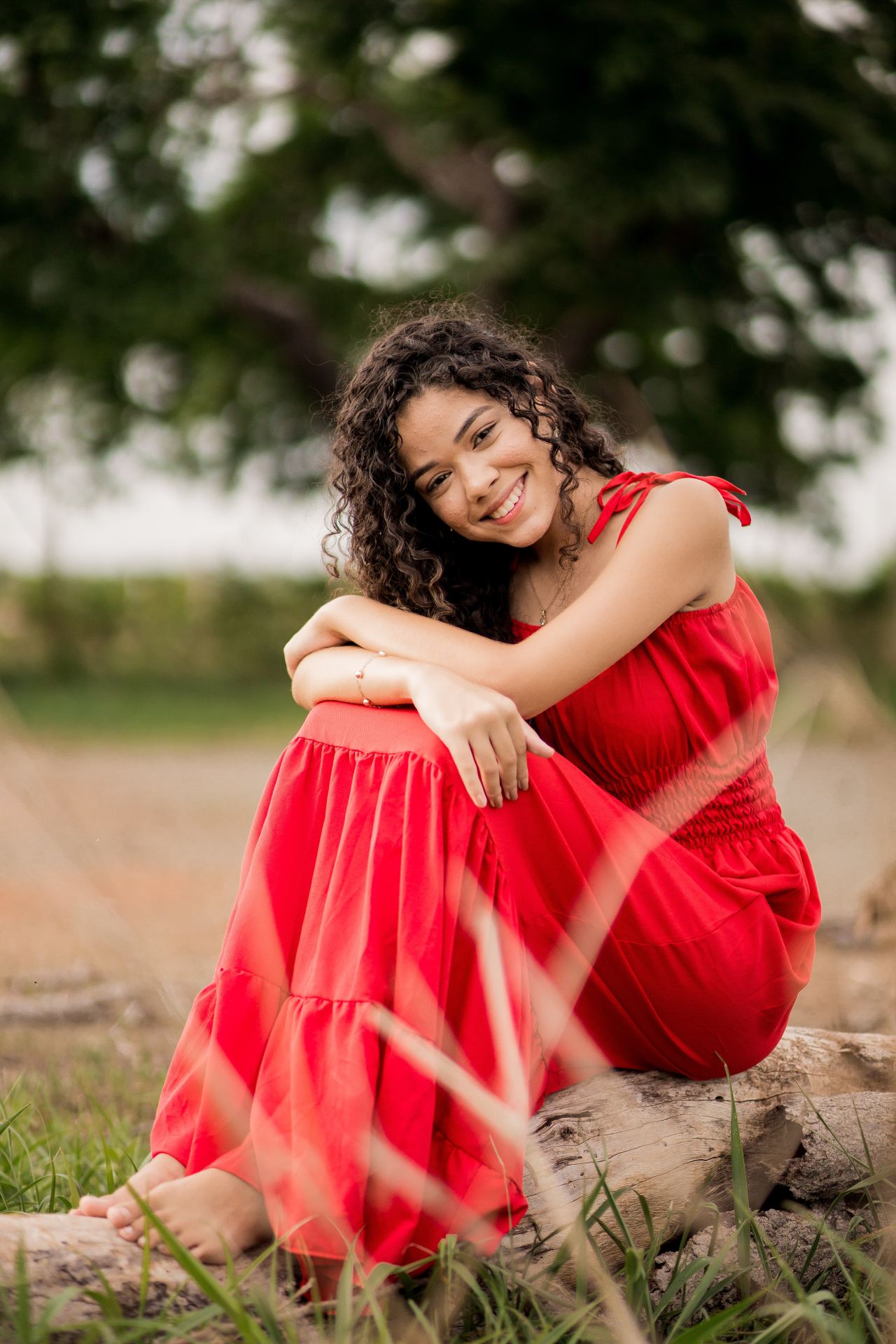 woman in red tube dress sitting on brown sand during daytime