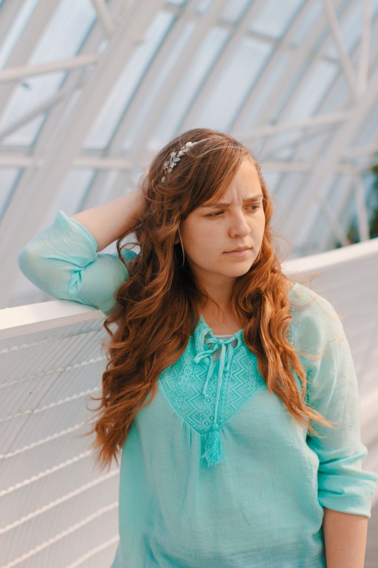 woman holding head near white handrail