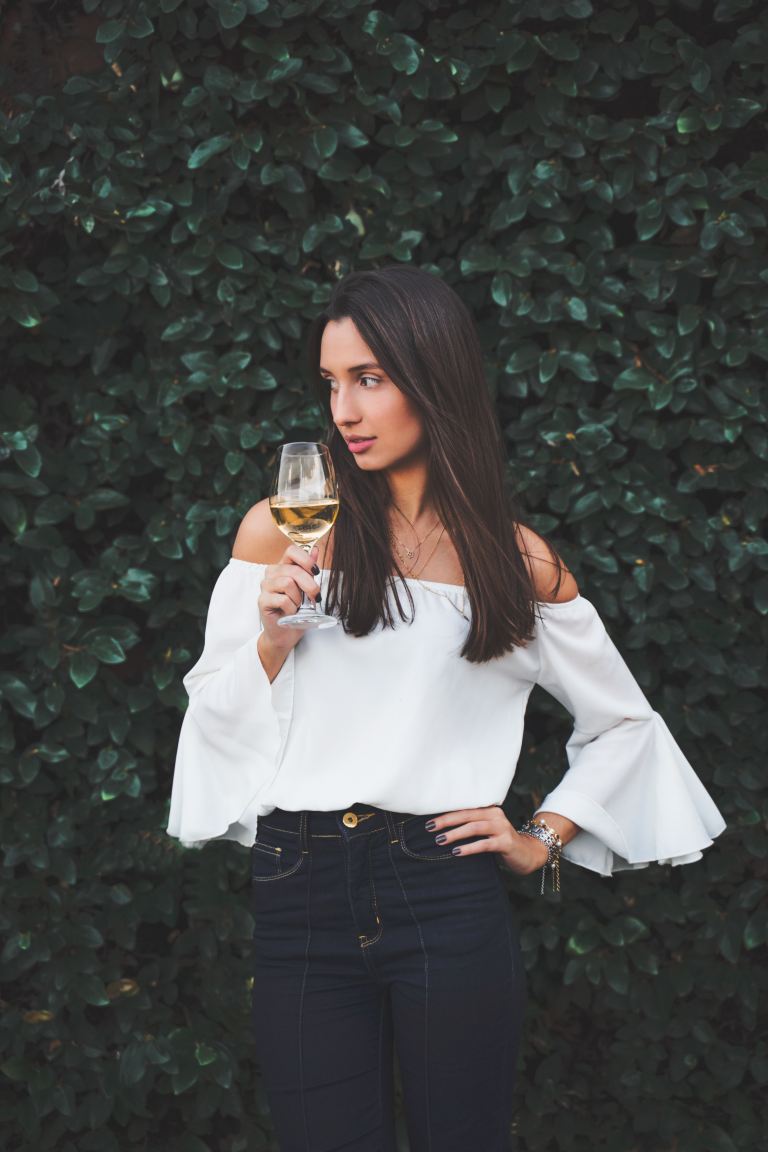 woman in white long sleeve shirt holding clear drinking glass