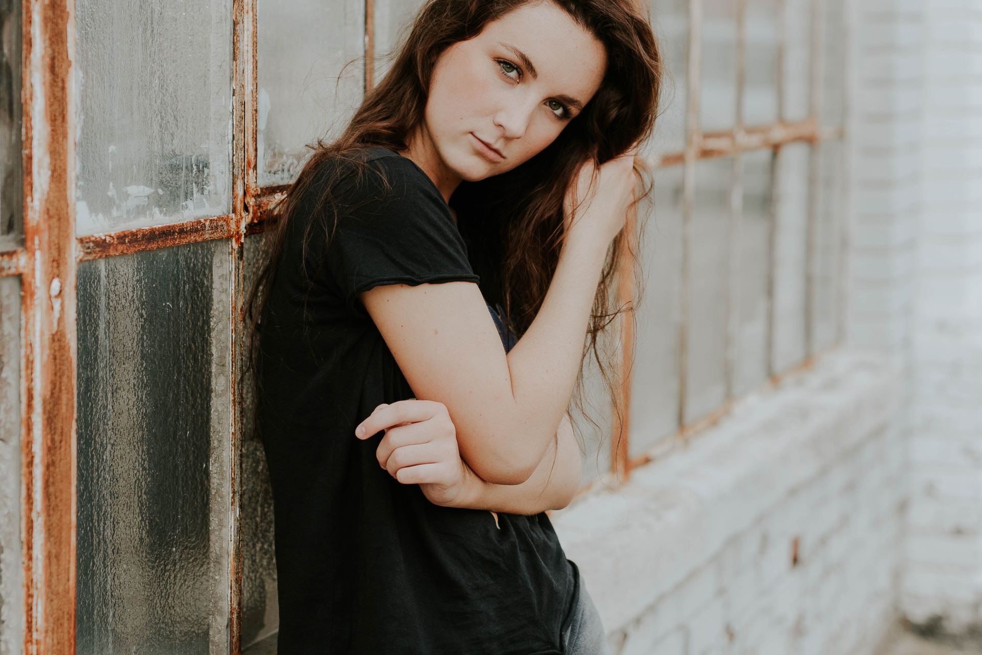 woman and black crew-neck T-shirt lying beside glass window