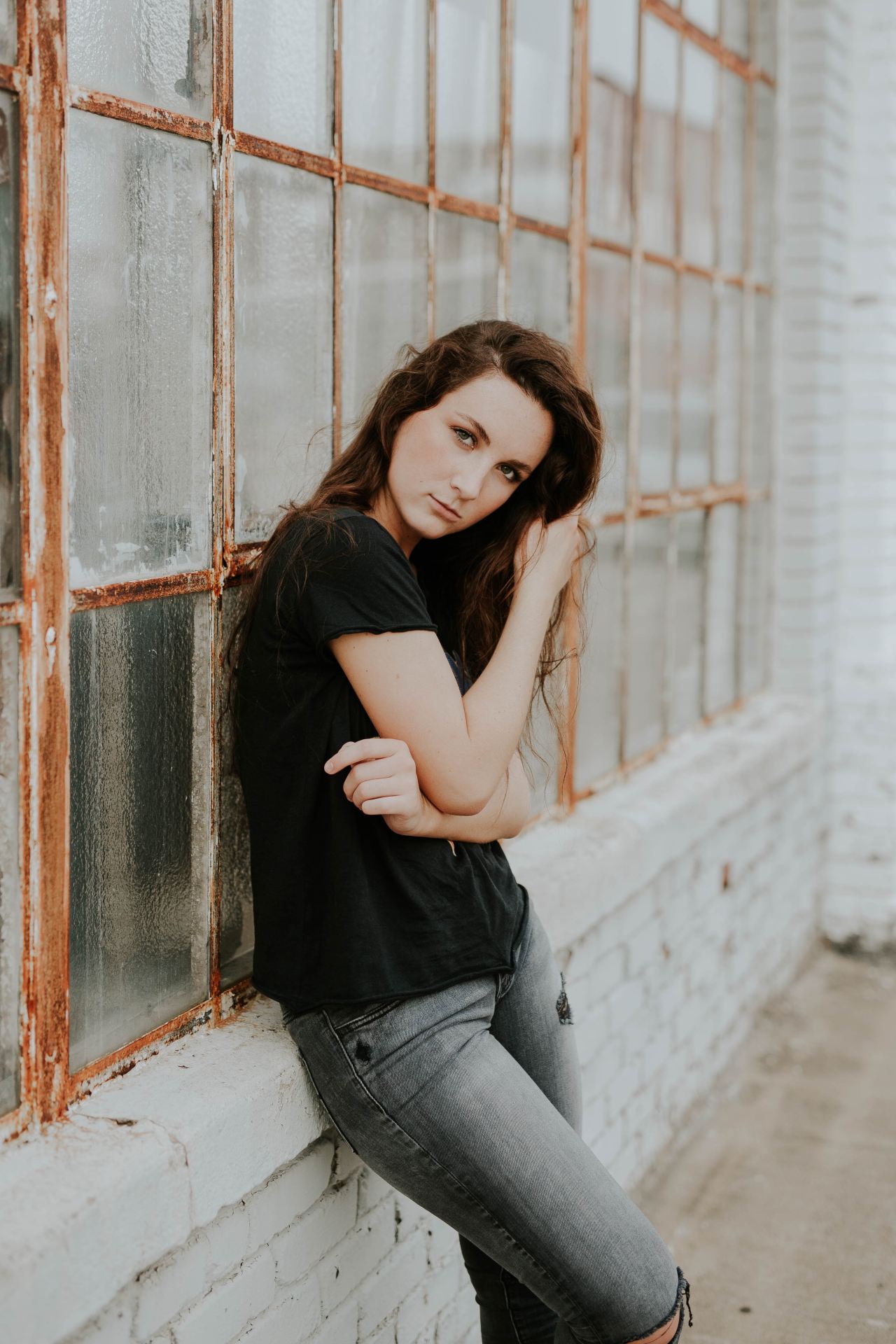 woman and black crew-neck T-shirt lying beside glass window