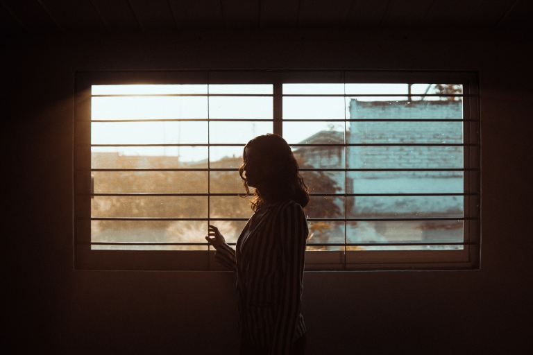 woman in white and black stripe shirt standing near window