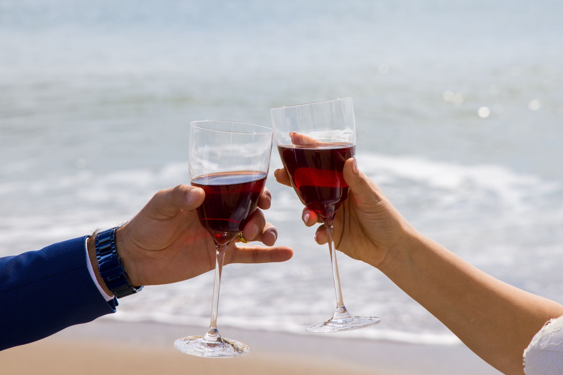 2 person holding clear wine glass with red wine during daytime