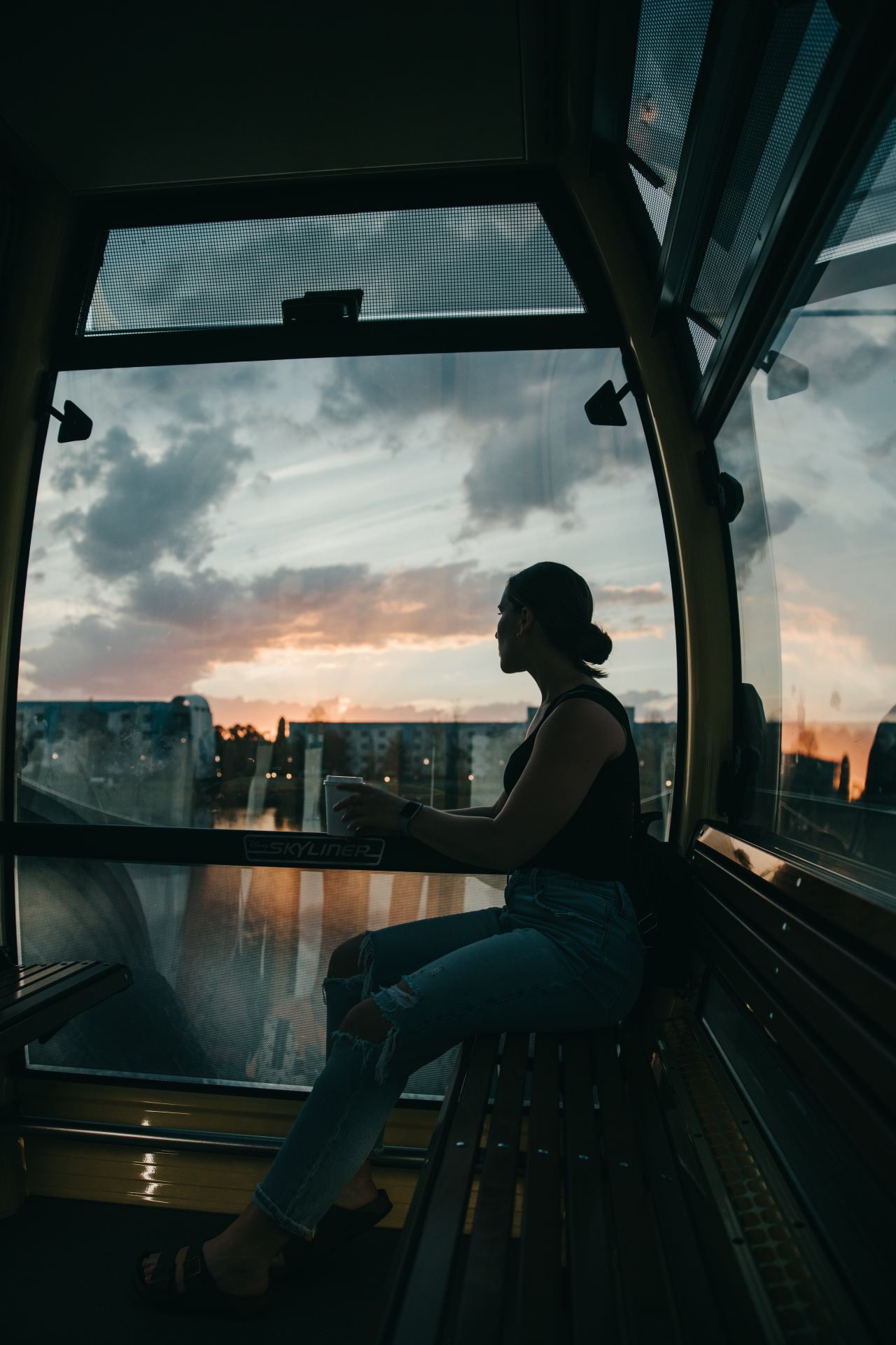 woman in black tank top sitting on window during daytime