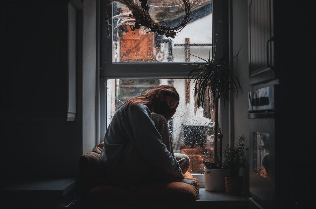 woman in gray long sleeve shirt sitting on window during daytime