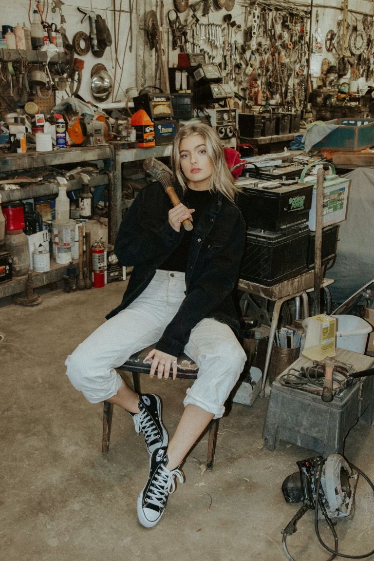 woman in black leather jacket and white pants sitting on black chair