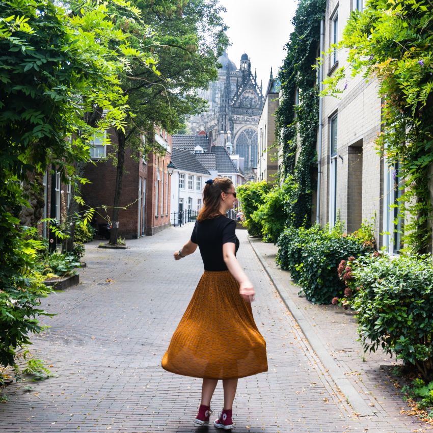 woman in black long sleeve shirt and red skirt walking on sidewalk during daytime