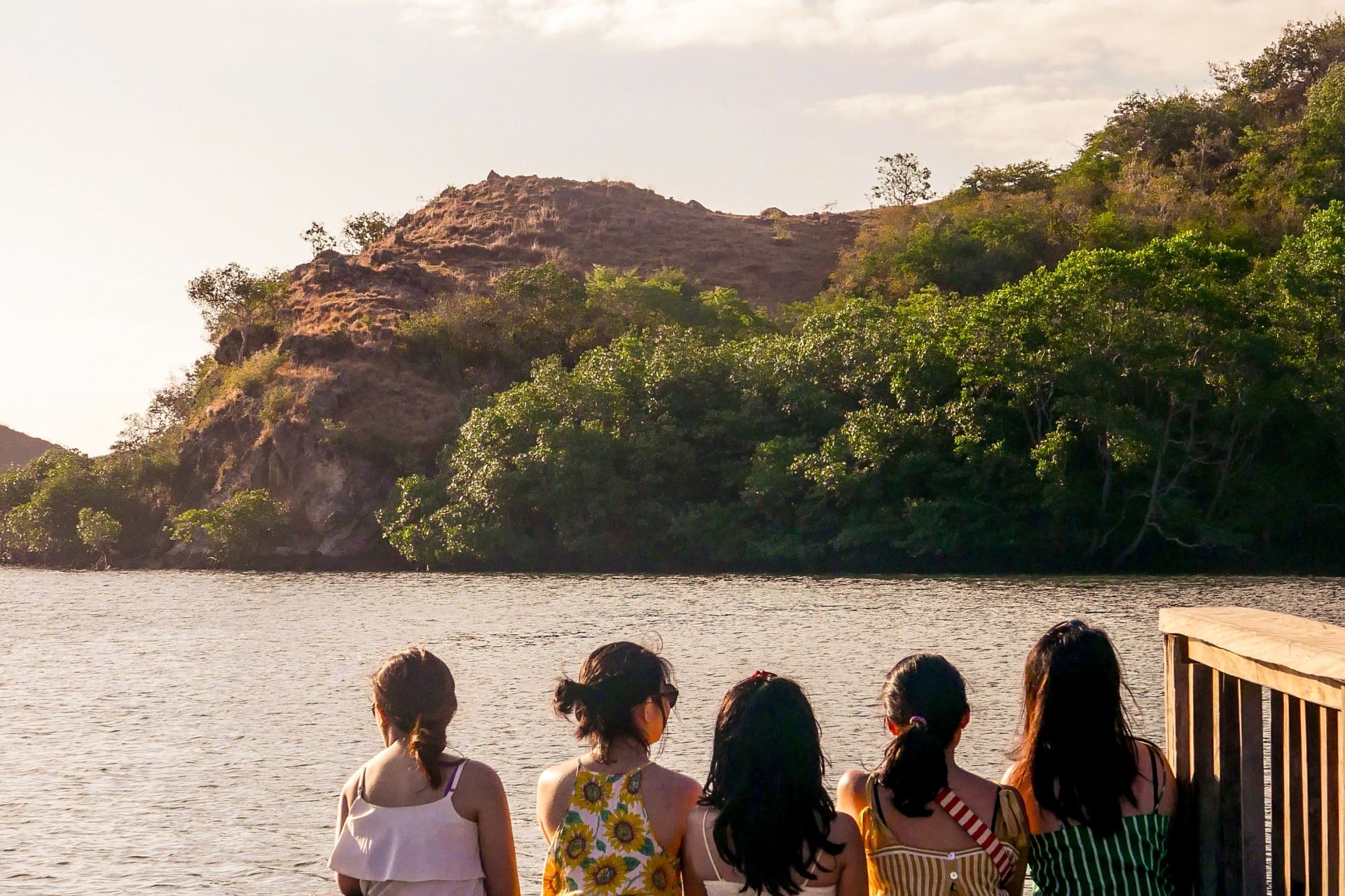 group of people sitting on brown wooden bench near body of water during daytime