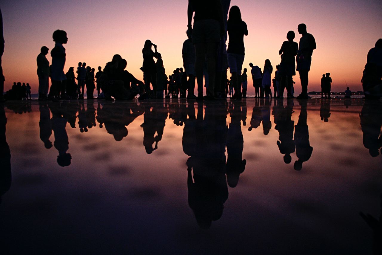 silhouette of people standing on mirror during golden hour