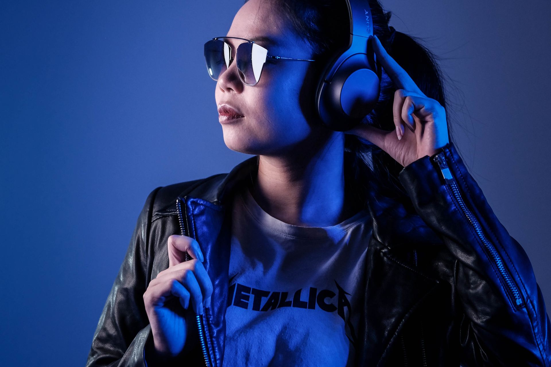 woman in black leather jacket wearing blue sunglasses