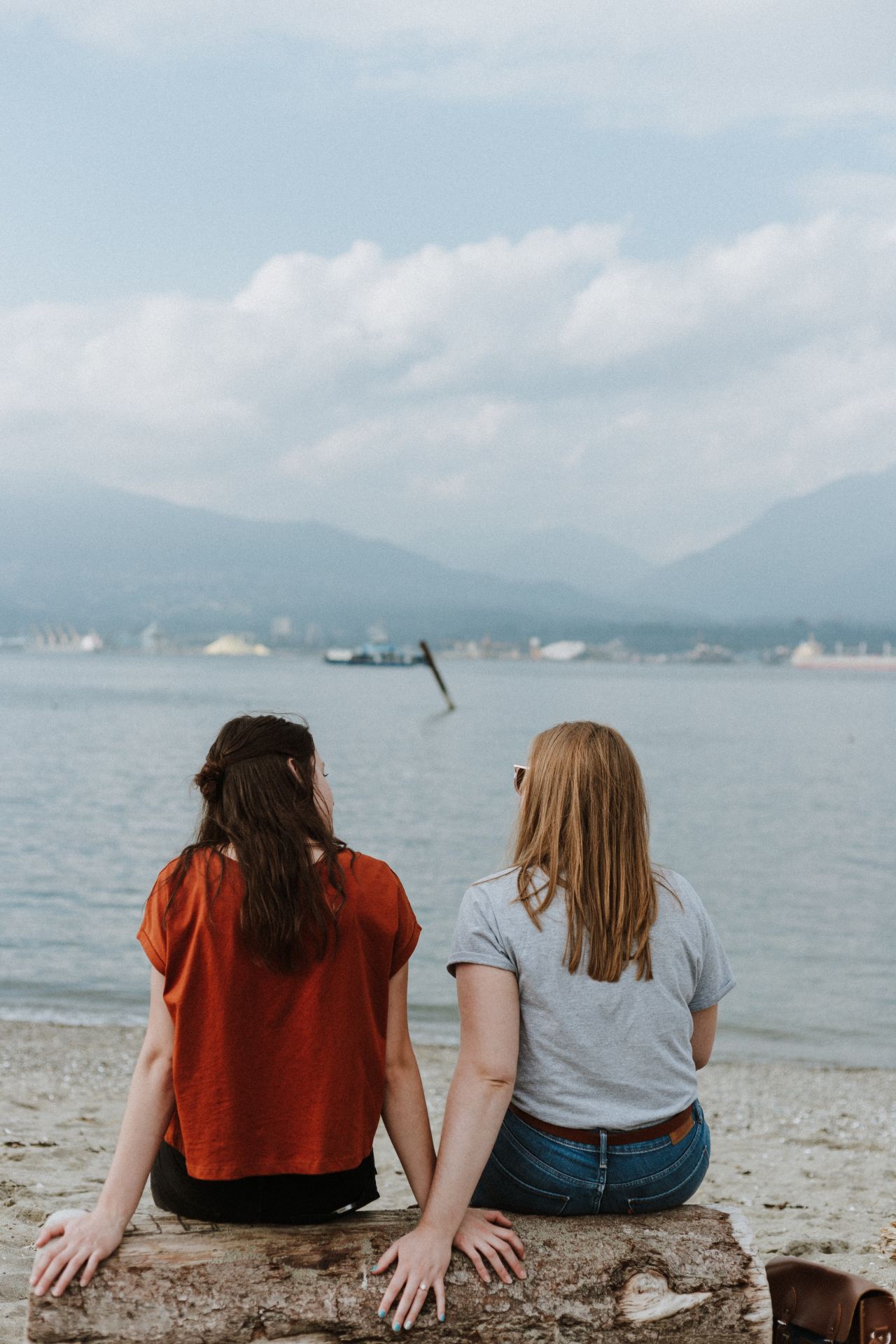 two women sitting on log