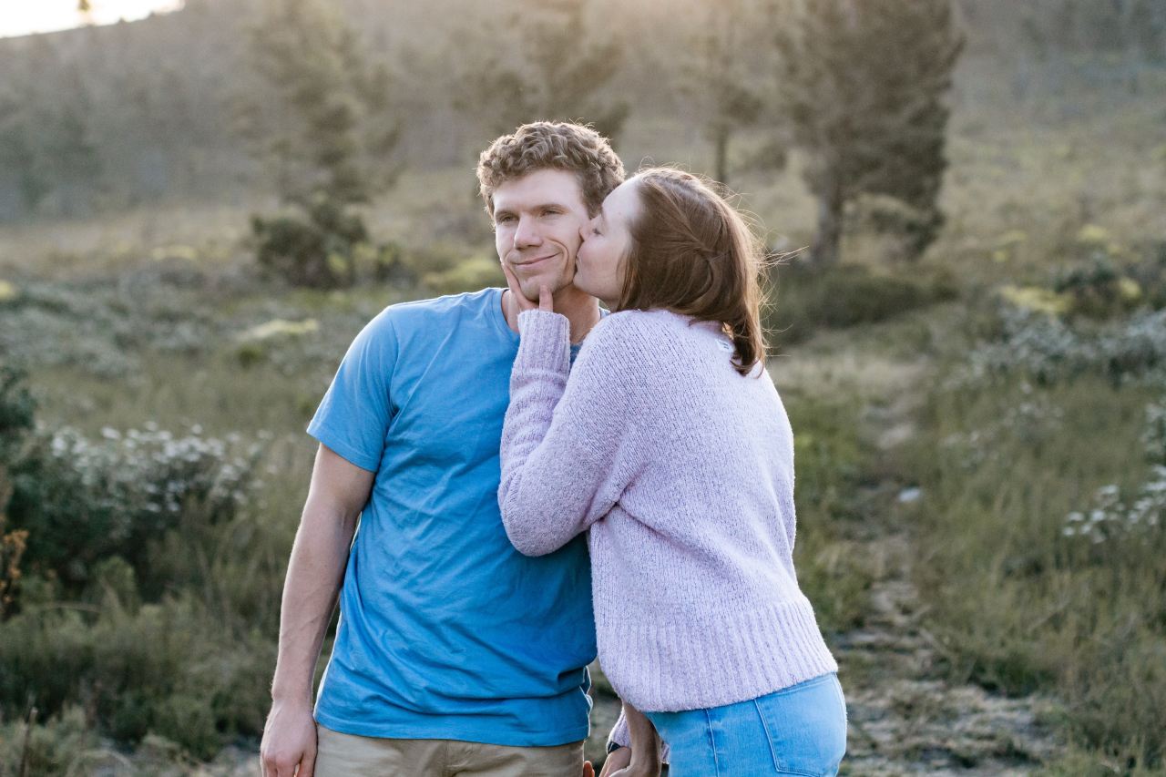 man in blue crew neck t-shirt hugging woman in white long sleeve shirt