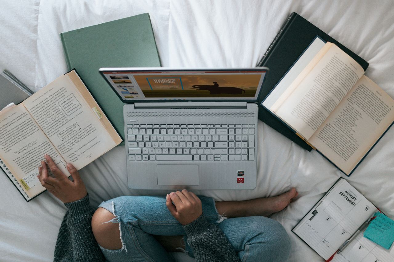 person in blue denim jeans sitting on bed with macbook pro