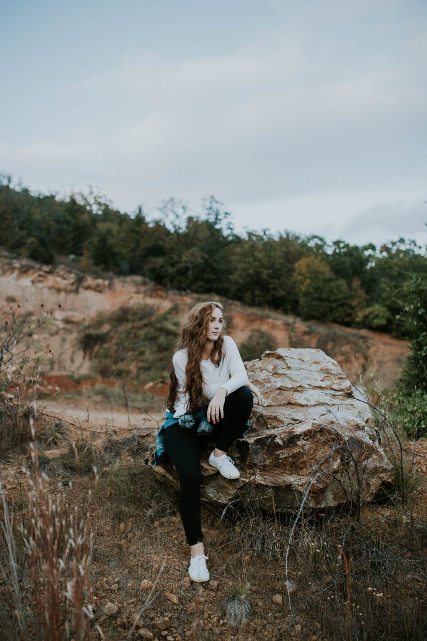 woman sitting on stone boulder outdoor