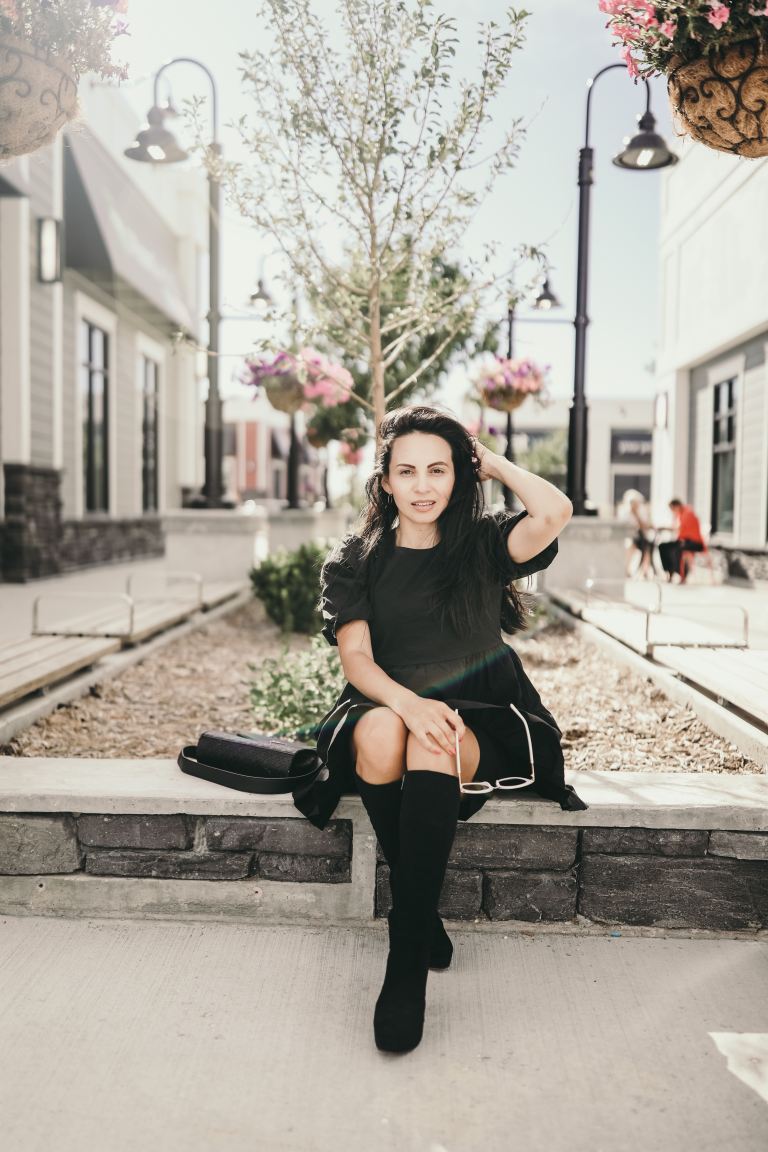 woman in black long sleeve shirt and black pants sitting on concrete bench during daytime