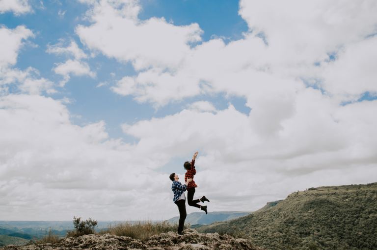 man lifting woman on top of the mountain