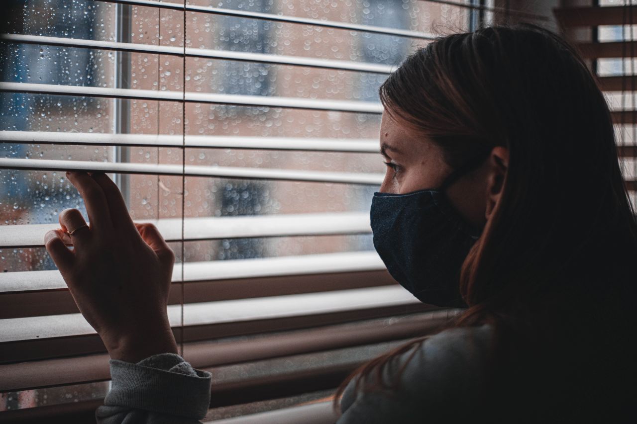 person in black hoodie near white window blinds