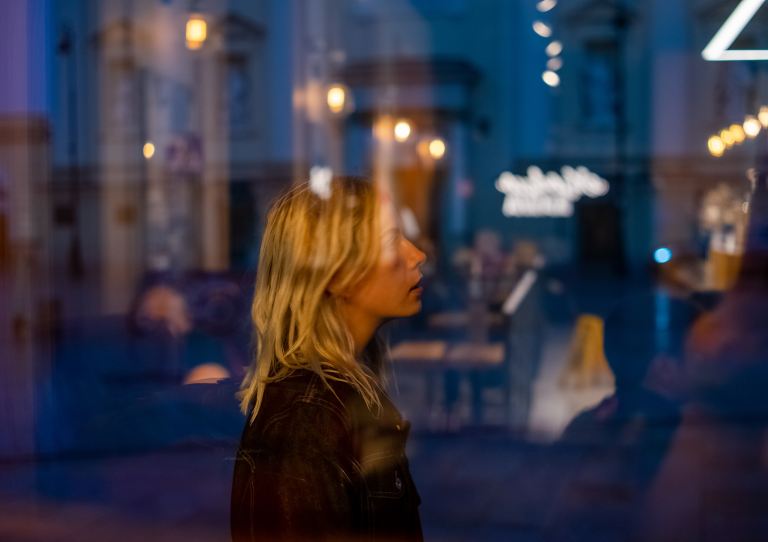 woman in black leather jacket standing in front of white and blue glass wall