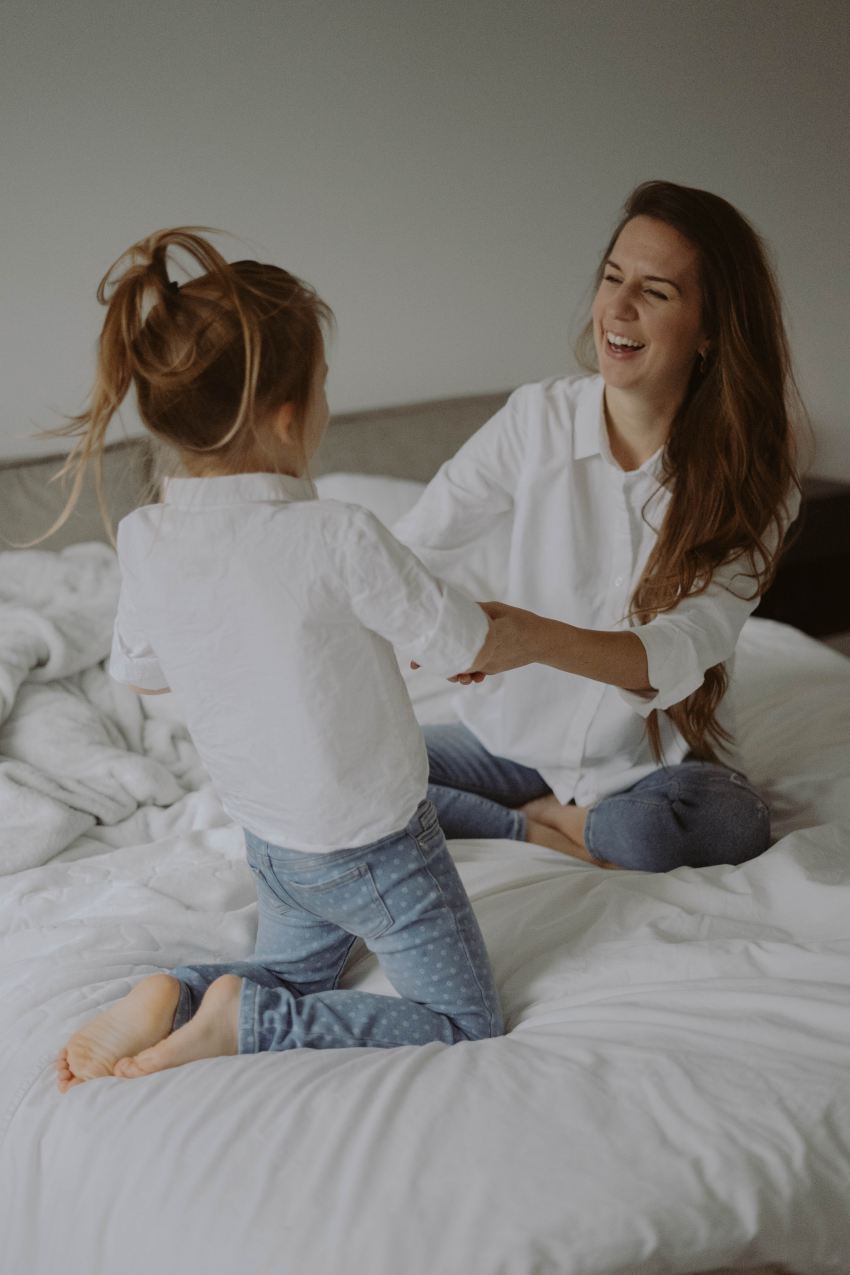 woman in white long sleeve shirt and blue denim jeans sitting on bed