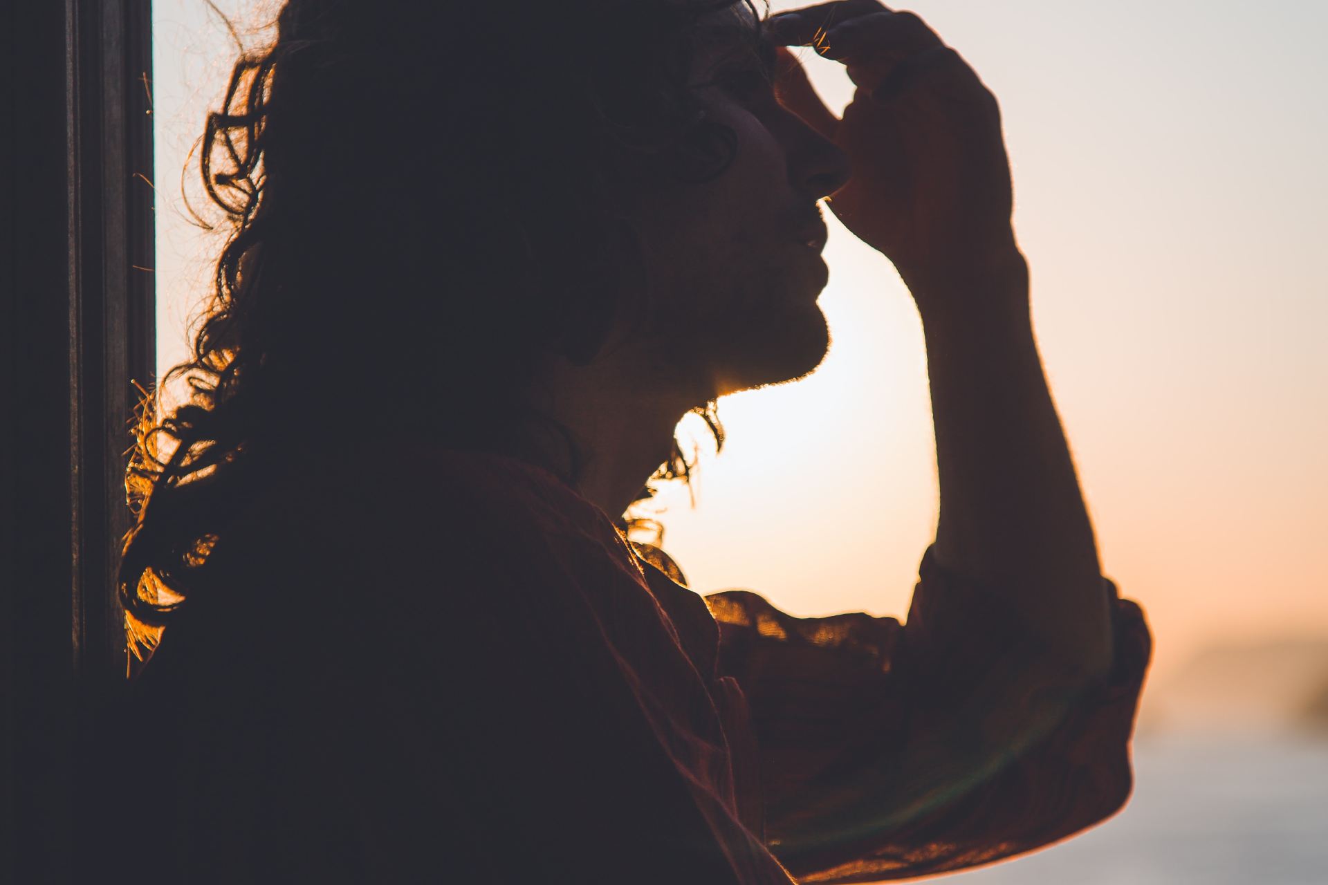 man holding forehead under sunset