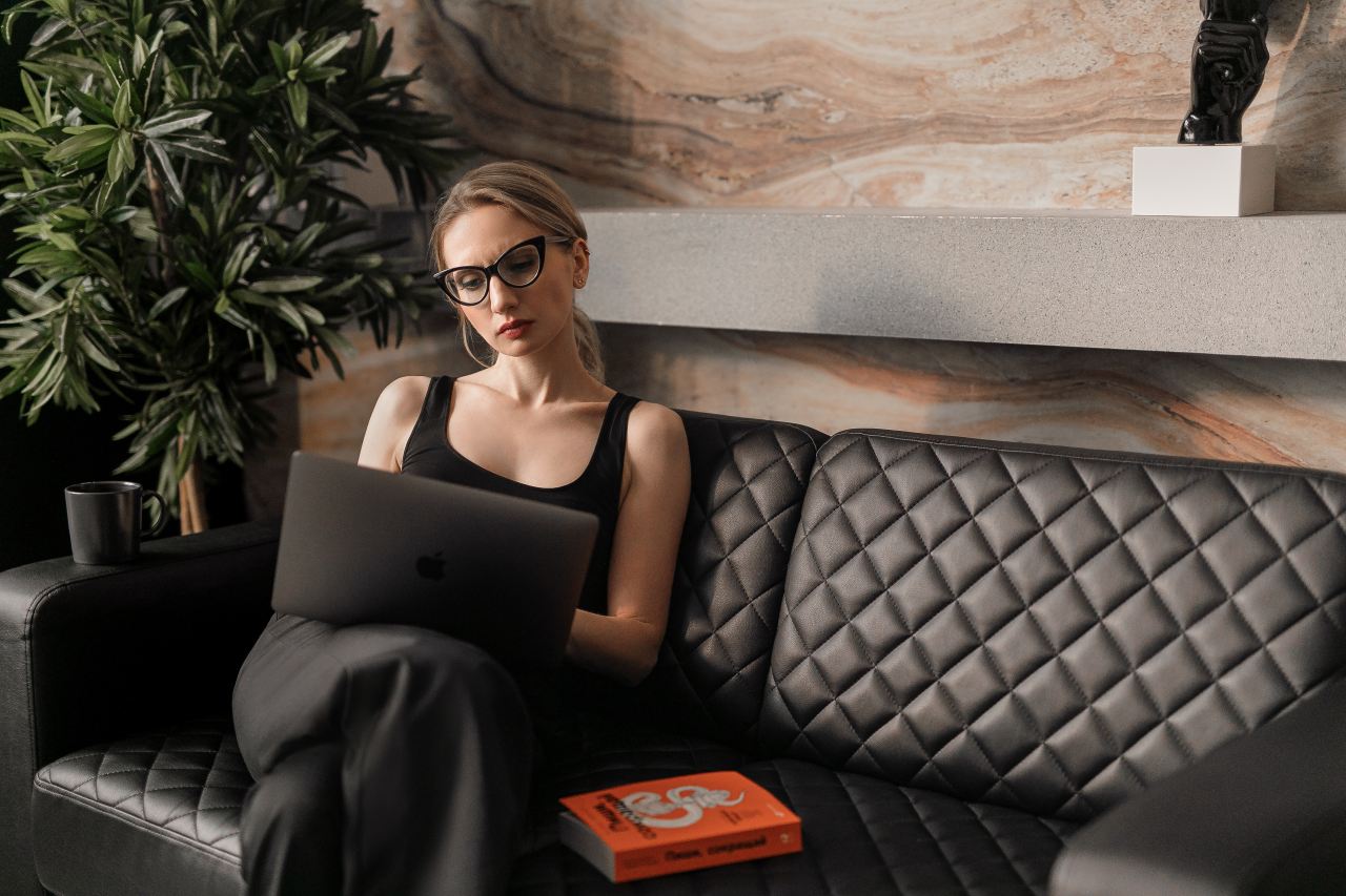 woman in black tank top wearing sunglasses sitting on black leather couch