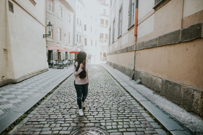 woman in black pants walking on sidewalk during daytime