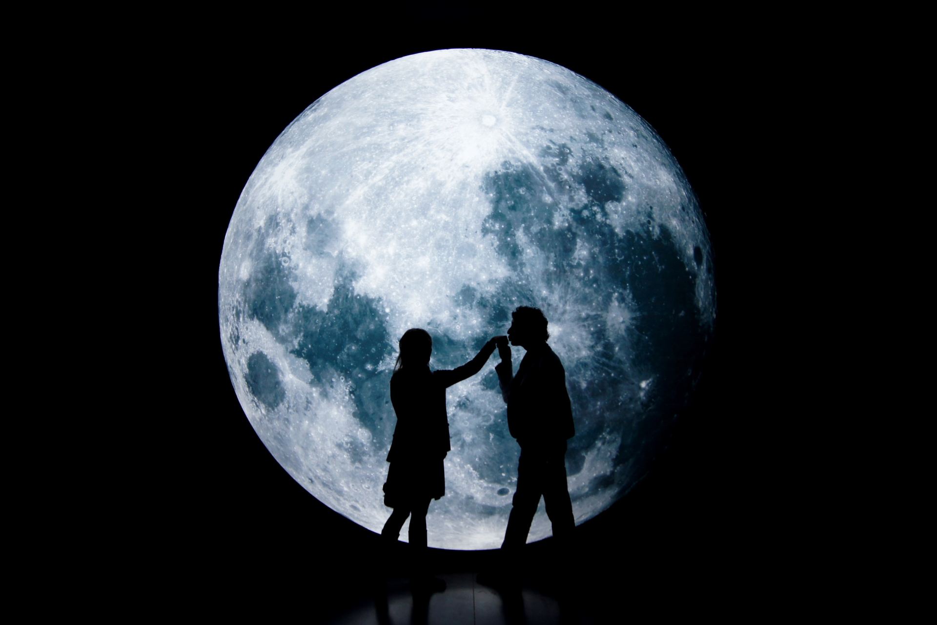 man and woman standing on a round moon