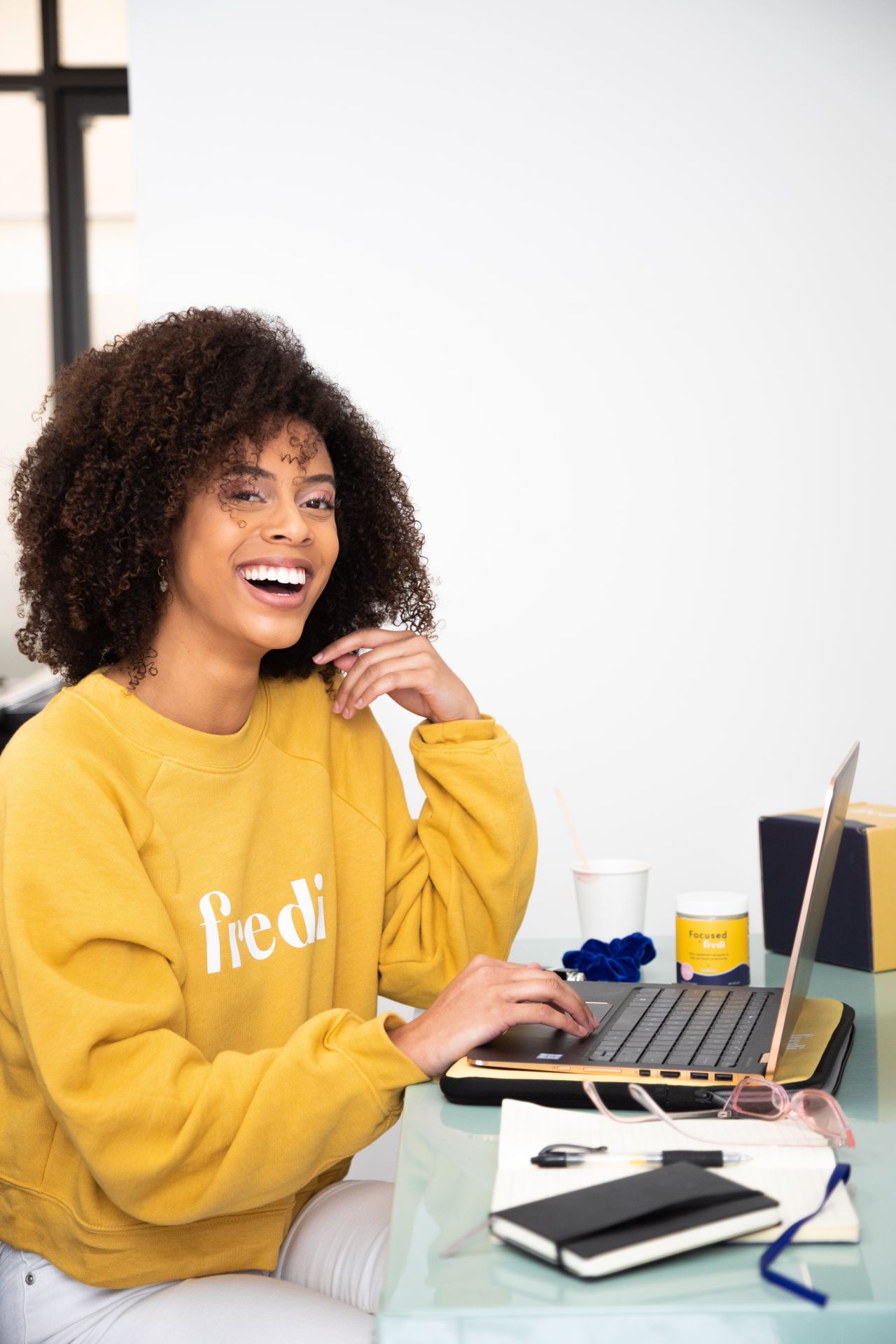 woman in yellow sweater sitting beside table with laptop computer