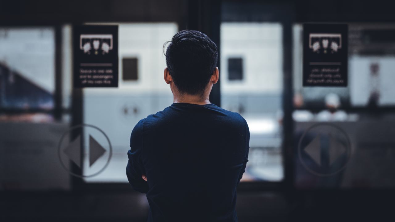 man wearing blue top facing glass door