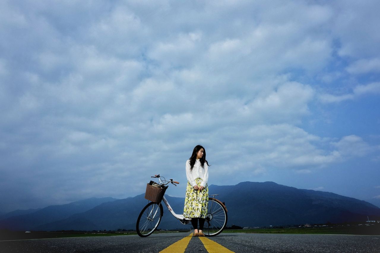 woman standing beside bike on road