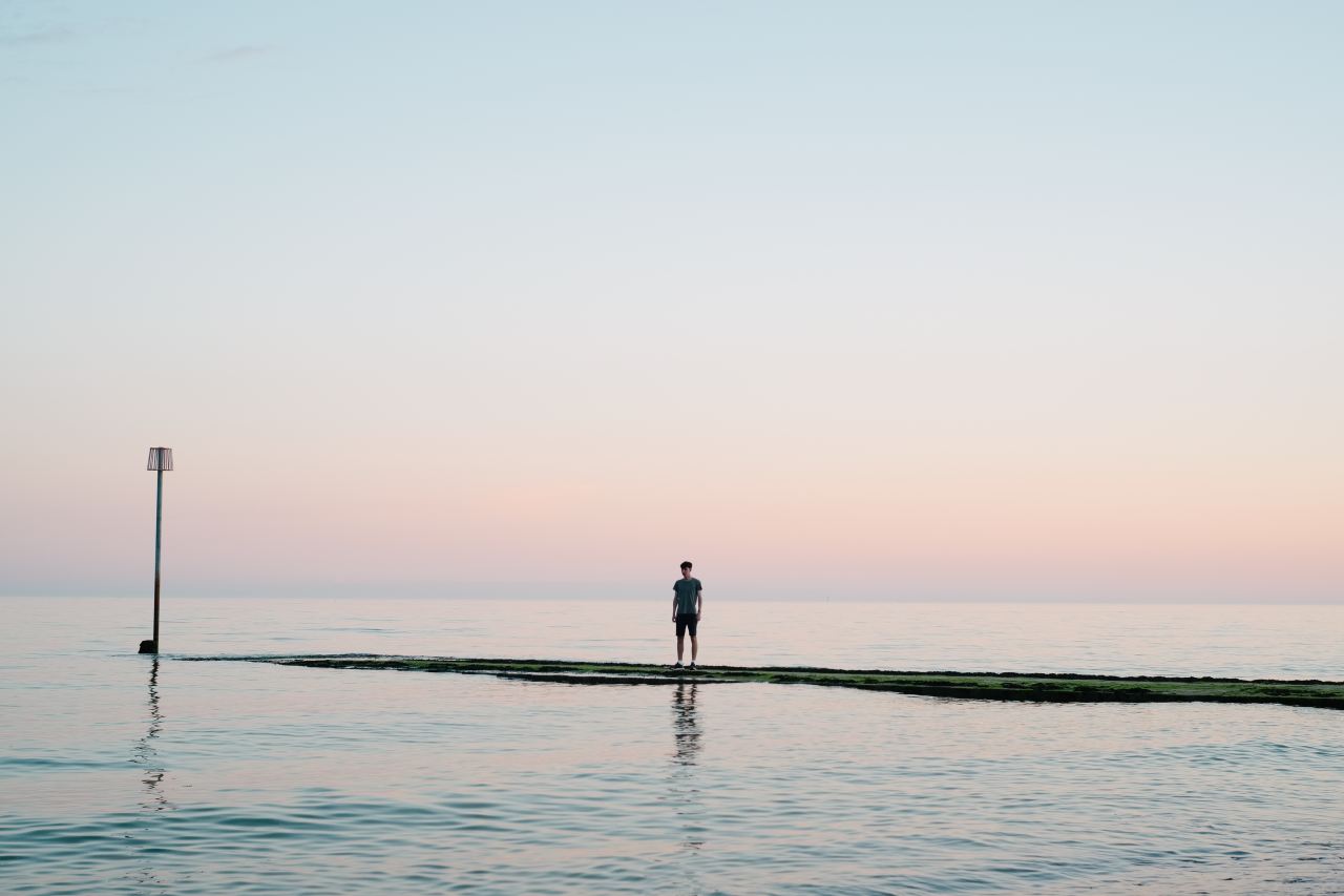 man standing on dock between body of water