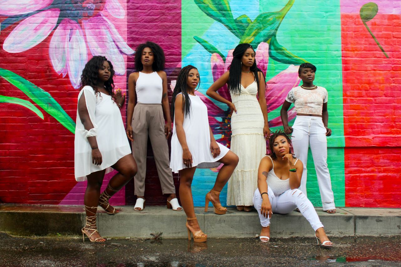 six women wearing white pants posing