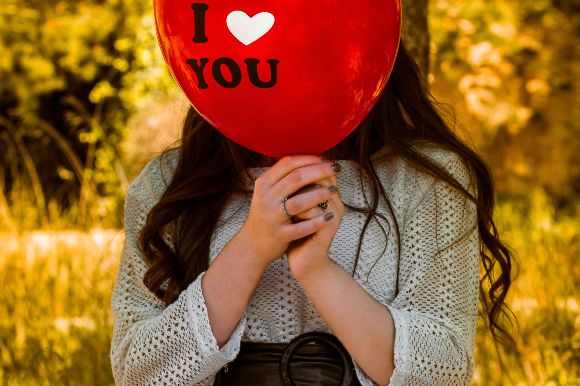 woman in gray sweater holding red balloon