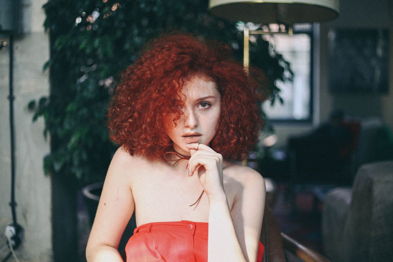 woman in orange tube top touching her chin